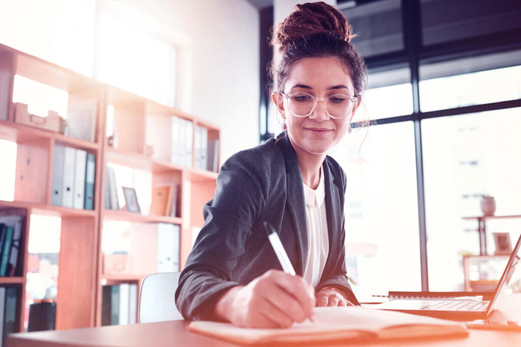 woman writing in notebook in office setting