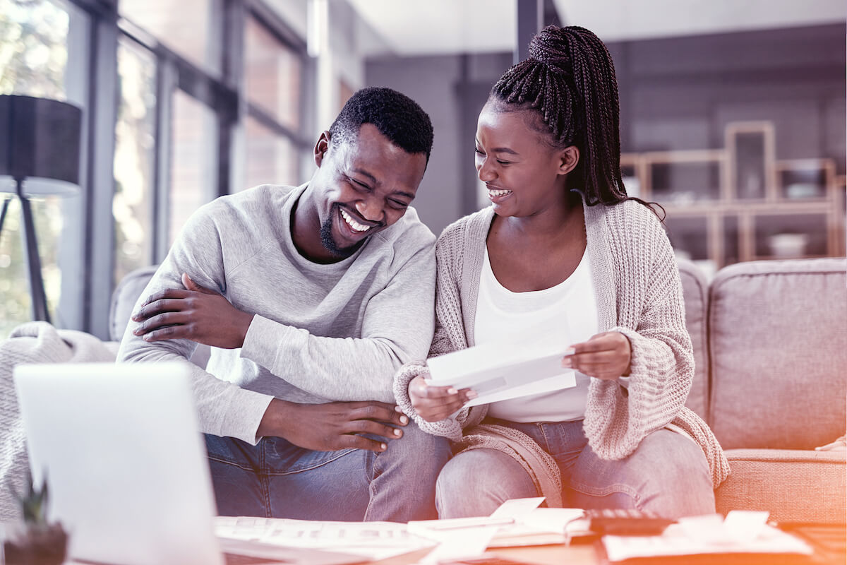 young couple looking happy with paperwork in living room